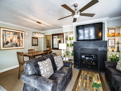Suite living area with leather sofas, fireplace, dining table, and large wall-mounted TV.