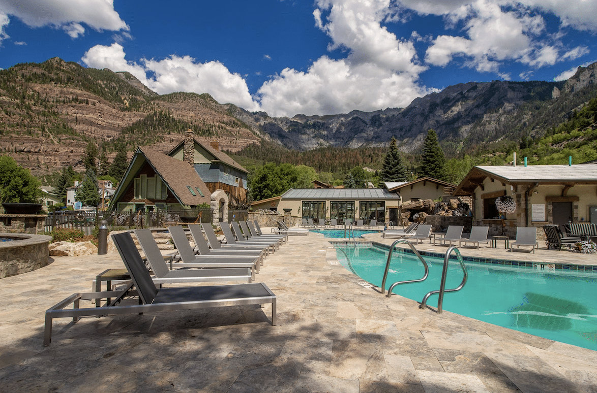 Outdoor resort pool with lounge chairs overlooking the dramatic San Juan Mountains in Ouray, Colorado.